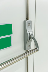 Closed up latch and door handle of emergency exit. Push bar and rail for exit.