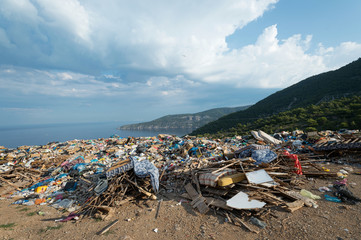 Piles of waste at landfill next to sea. Bad waste management, ecology, enviromental issues concept