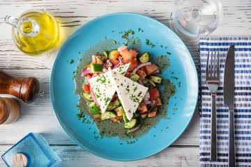greek salad with chunk feta cheese on blue plate