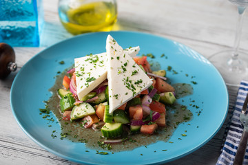 greek salad with chunk feta cheese on blue plate