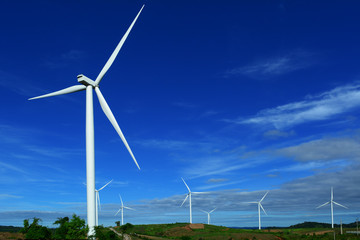 The white electric wind turbine with blue sky on low hill  at Petchaboon,Thailand