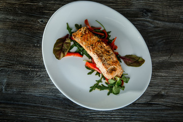 top view of baked salmon fillet with green salad and arugula
