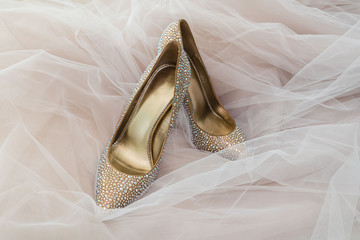 Wedding shoes bride Golden color with stones on the background of wedding tulle.