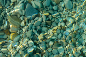 Blurred natural background. Pebbles through the clear sea water.