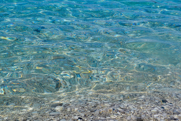 square background image of calm turquoise sea on shingle beach