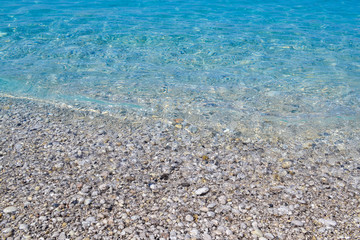 square background image of calm turquoise sea on shingle beach