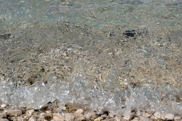 square background image of calm turquoise sea on shingle beach