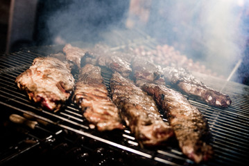 Meat on the grill. Grilled meat and spit-roasted meat during cooking