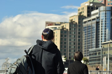 rear view of a Jewish person with the kippah standing in front of tall buildings background  in...