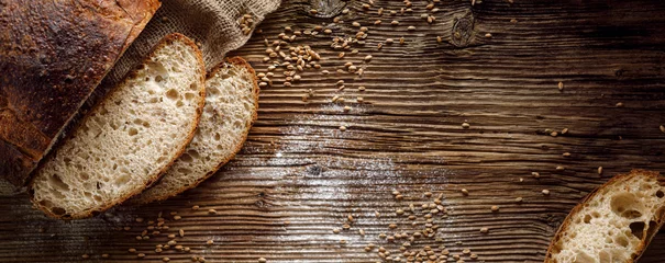 Gordijnen Brood, traditioneel zuurdesembrood in plakjes gesneden op een rustieke houten achtergrond, close-up, bovenaanzicht, kopieerruimte. Concept van traditionele bakmethoden voor gezuurd brood © zi3000