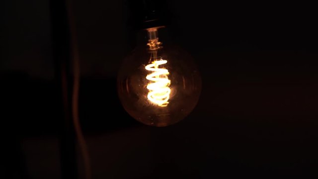 Tungsten light bulb lamp over black background. Concept of light and dark, idea, electricity at modern home.