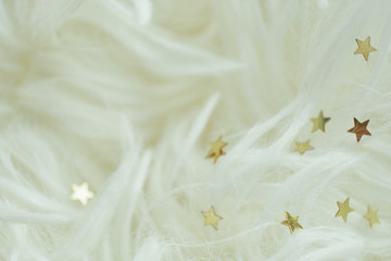 Obraz na płótnie Canvas scattered golden stars on white shaggy faux fur