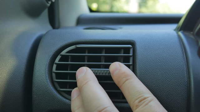 Close-up of hand adjusting air vents to change wind direction inside the car. Too cool or too warm air condition.