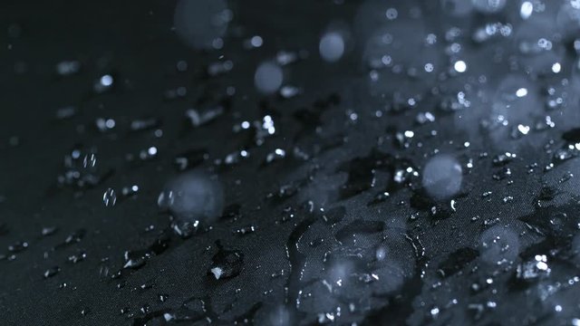 Super slow motion of falling water drops on waterproof cloth texture in detail. Filmed on high speed cinema camera, 1000 fps.