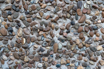 Concrete plaster interspersed with many smooth river stones. Decorative wall.
