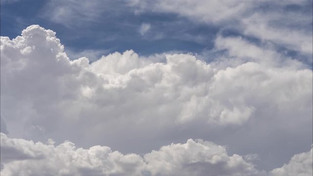 Time lapse of thick fluffy clouds rolling in blue sky