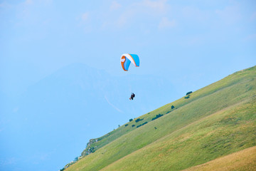 Paraglider flying over the Garda Lake (Lago di Garda or Lago Benaco). Paragliding on Monte Baldo. Panorama of the gorgeous Garda lake surrounded by mountains, Malcesine, Italy