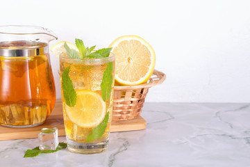 Glass of iced tea with mint and lemon on marble table. Cold drink.
