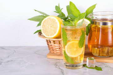 Glass of iced tea with mint and lemon on marble table. Cold drink.