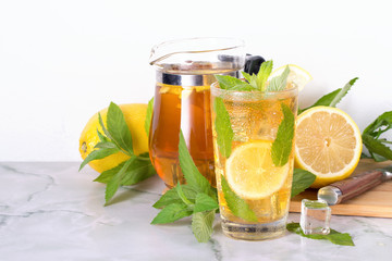 Glass of iced tea with mint and lemon on marble table. Cold drink.