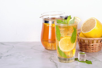 Glass of iced tea with mint and lemon on marble table. Cold drink.