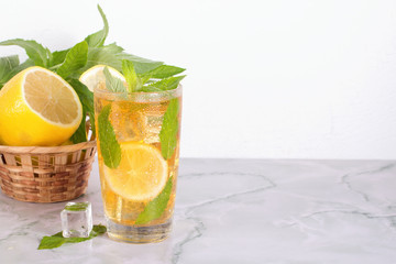 Glass of iced tea with mint and lemon on marble table. Cold drink.