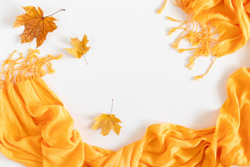 Autumn cozy composition. Dried autumn leaves, yellow scarf on white background. Fall relax concept. Flat lay, top view, copy space