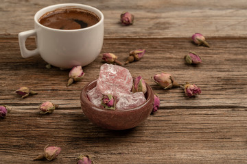 coffee and turkish delight on a wooden table decorated with dried roses