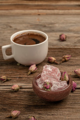 coffee and turkish delight on a wooden table decorated with dried roses