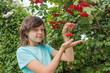 Teenage girl and viburnum berries on branches among foliage