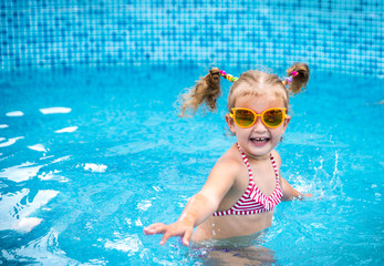 Little beautiful girl resting in the pool and learning to swim