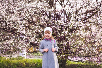 Child on pink flowers of sakura tree background. Girl enjoying cherry blossom or sakura. Cute child enjoy warm spring day. Aromatic blossom concept. Girl tourist posing near sakura. Tender bloom.