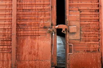 Red railway freight car with an open door. The lock on an ajar door with a seal.