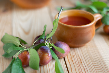 Sweet red plums with leaves on the wooden rustic table, selective focus