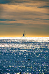View from the beach in front of Nice to a sailboat at the French Riviera in front of a cloudy sky...