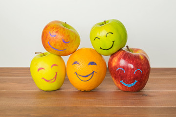 Different apples and orange with funny faces, tolerance, originality or friendship concept.