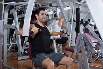 Fototapeta na wymiar Man training on fitness machine in gym