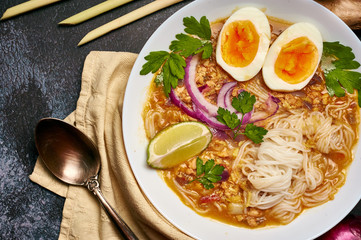 Mohinga at dark background in white plate. Mohinga is a burmese cuisine fish soup with catfish,...