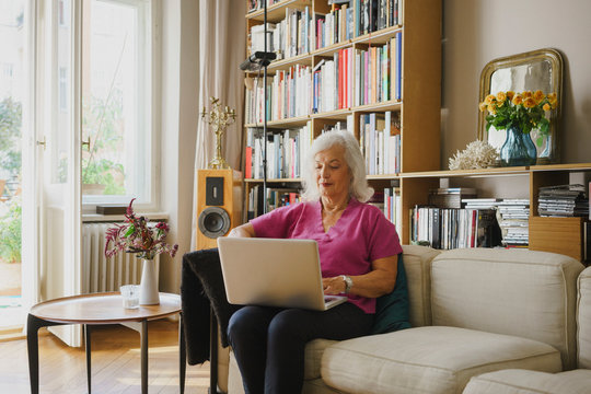 Senior woman using laptop on living room sofa