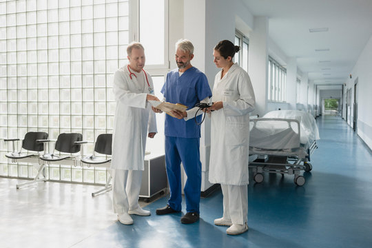 Doctors discussing medical chart in hospital corridor