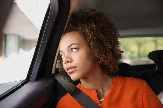 Thoughtful young woman riding in car, looking out window