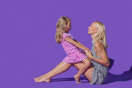 Mother and daughter in striped dresses on purple background