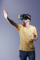 technology, gaming, entertainment and people concept - young man with virtual reality headset or 3d glasses. Studio shot, gray background.
