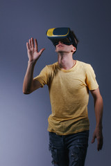 technology, gaming, entertainment and people concept - young man with virtual reality headset or 3d glasses. Studio shot, gray background.