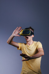 technology, gaming, entertainment and people concept - young man with virtual reality headset or 3d glasses. Studio shot, gray background.