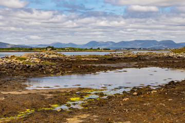Bay with low tide and mountains in Carraroe