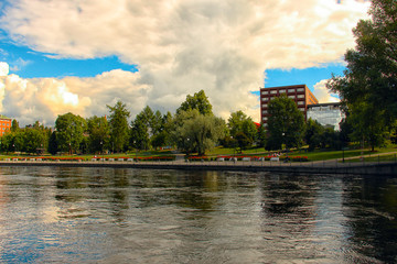 city park by the river with reflections in the water and beautiful clouds
