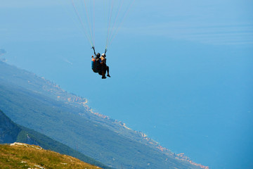 Paraglider flying over the Garda Lake (Lago di Garda or Lago Benaco). Paragliding on Monte Baldo. Panorama of the gorgeous Garda lake surrounded by mountains, Malcesine, Italy