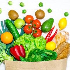 Paper bag of different health food on white wooden background. Top view