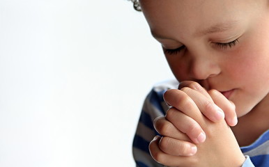 boy praying to God stock image with hands held together with closed eyes  stock photo